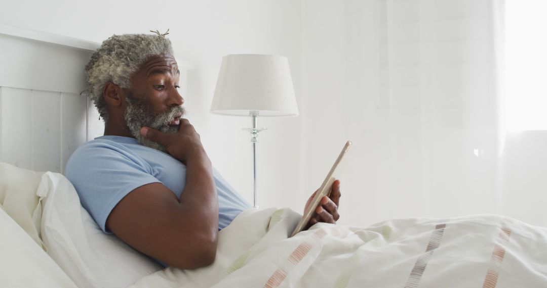 Elderly Man Relaxing in Bed While Using Tablet - Free Images, Stock Photos and Pictures on Pikwizard.com