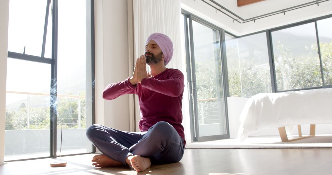 Man Sitting in Meditation Practicing Yoga in Bright Bedroom