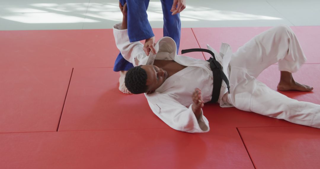 Two Judo Fighters Practicing Techniques on Red Gym Mats