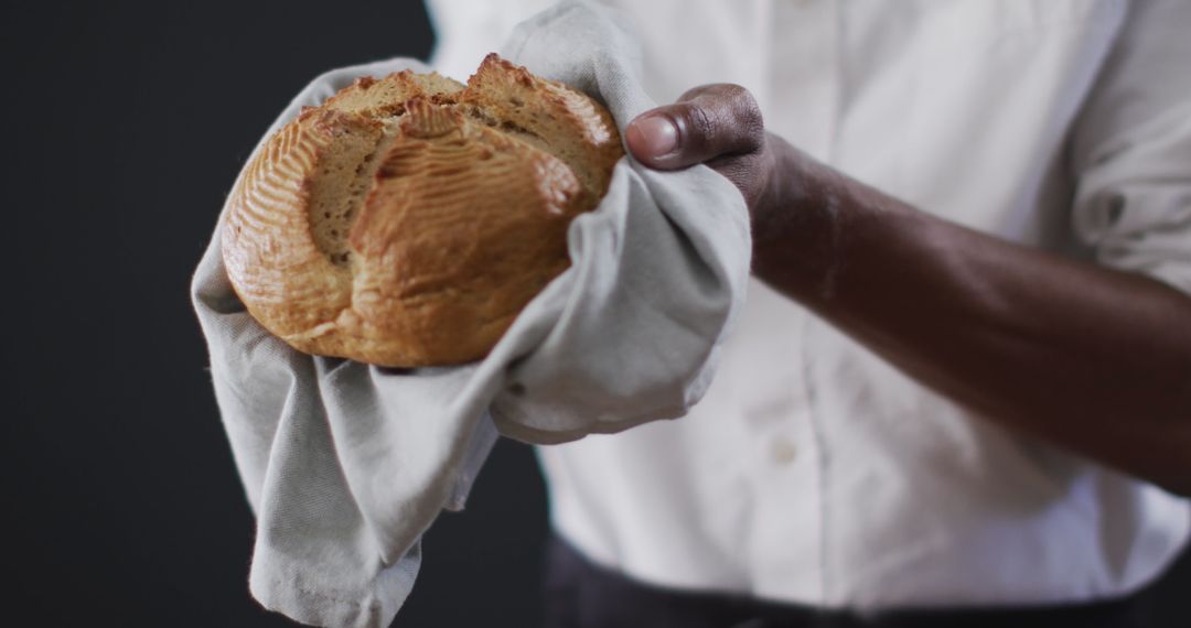 Chef Holding Rustic Homemade Bread on Dark Background