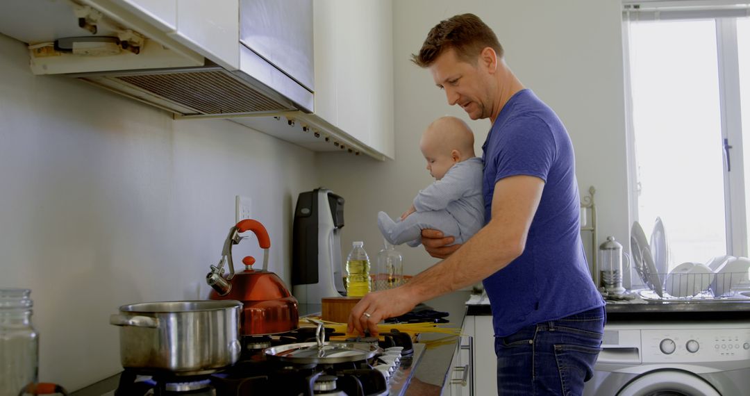 A man exemplifies modern parenting by cooking and holding a baby simultaneously. - Free Images, Stock Photos and Pictures on Pikwizard.com
