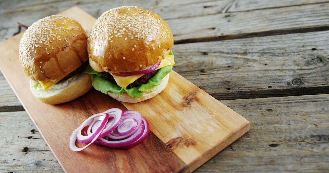 Two Cheeseburgers with Lettuce and Red Onion on Wooden Cutting Board - Free Images, Stock Photos and Pictures on Pikwizard.com