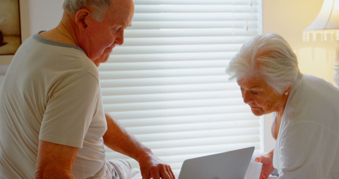 Senior Couple Enjoying Coffee Together While Using Laptop