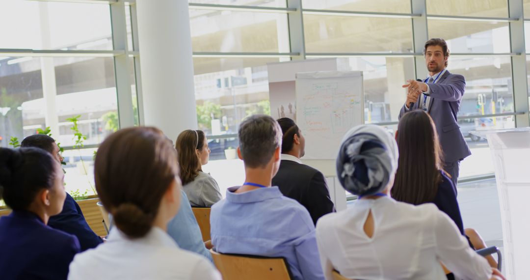 A Caucasian man speaks publicly at a business seminar, standing by a clipboard in 4k. - Free Images, Stock Photos and Pictures on Pikwizard.com