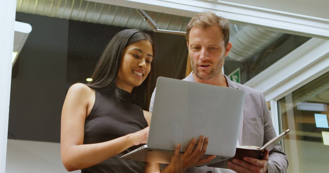 Diverse Team Collaborating on Project with Laptops in Office