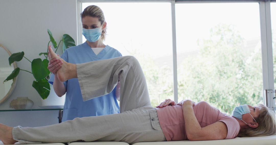 Physical therapist assisting elderly woman with leg exercise in clinic - Free Images, Stock Photos and Pictures on Pikwizard.com