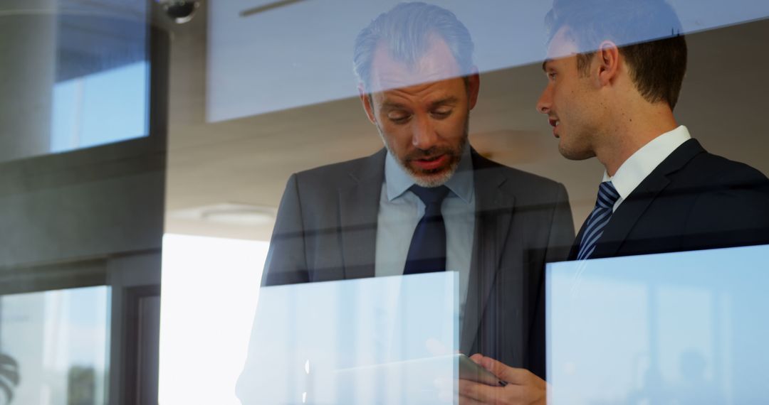 Businessmen Discussing Details Using Tablet by Office Window
