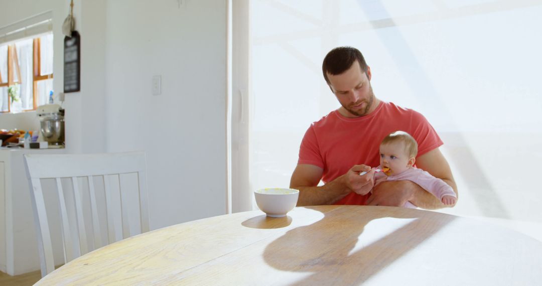 Father Feeding Baby in Bright Kitchen - Free Images, Stock Photos and Pictures on Pikwizard.com