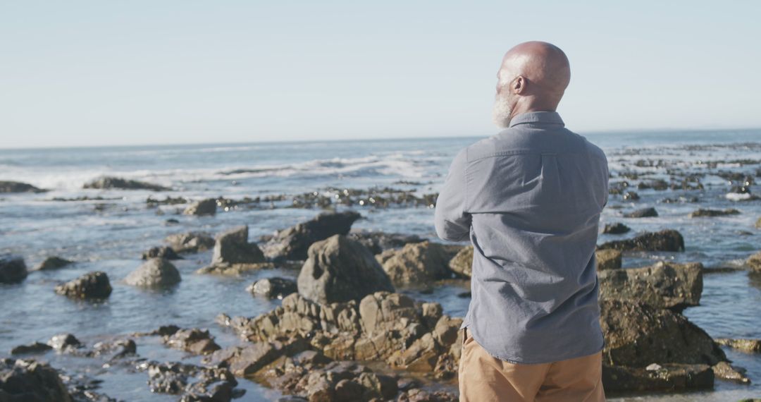 Pensive Bald Man Enjoying Scenic Ocean View at Rocky Beach - Free Images, Stock Photos and Pictures on Pikwizard.com