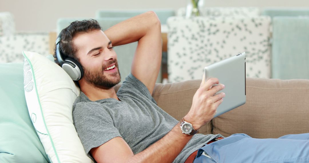 Man Relaxing on Couch with Headphones and Tablet - Free Images, Stock Photos and Pictures on Pikwizard.com