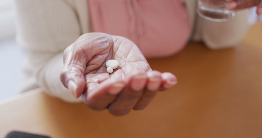 Senior african american woman sitting at table, taking pills - Free Images, Stock Photos and Pictures on Pikwizard.com