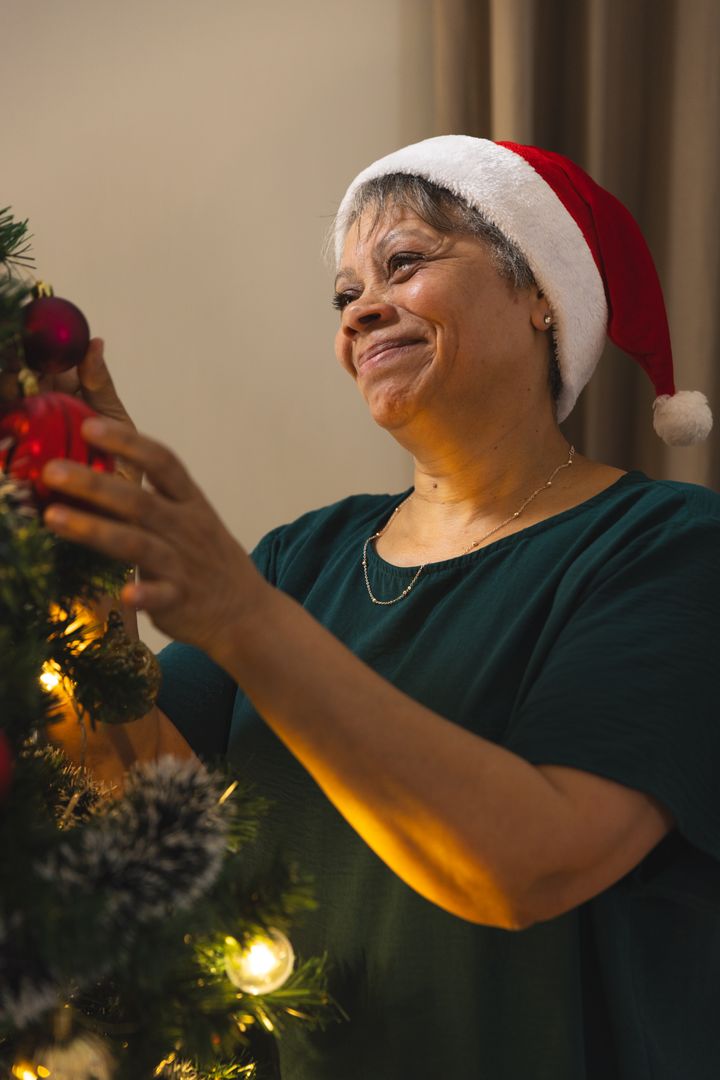Senior Woman Smiling While Decorating Christmas Tree Inside Home