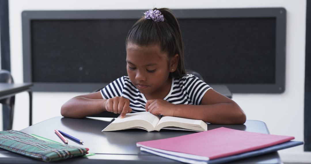 Young Girl Focused on Reading in Classroom