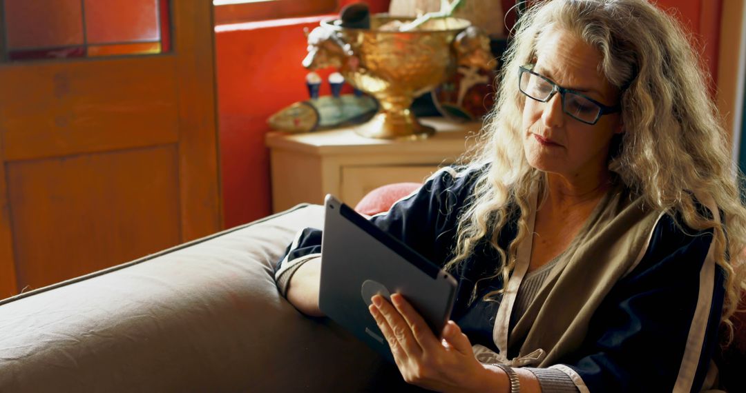 Senior Woman Reading Tablet on Comfortable Couch in Cozy Living Room - Free Images, Stock Photos and Pictures on Pikwizard.com