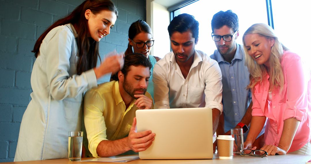 Diverse Team Engaged in Lively Discussion Around Laptop