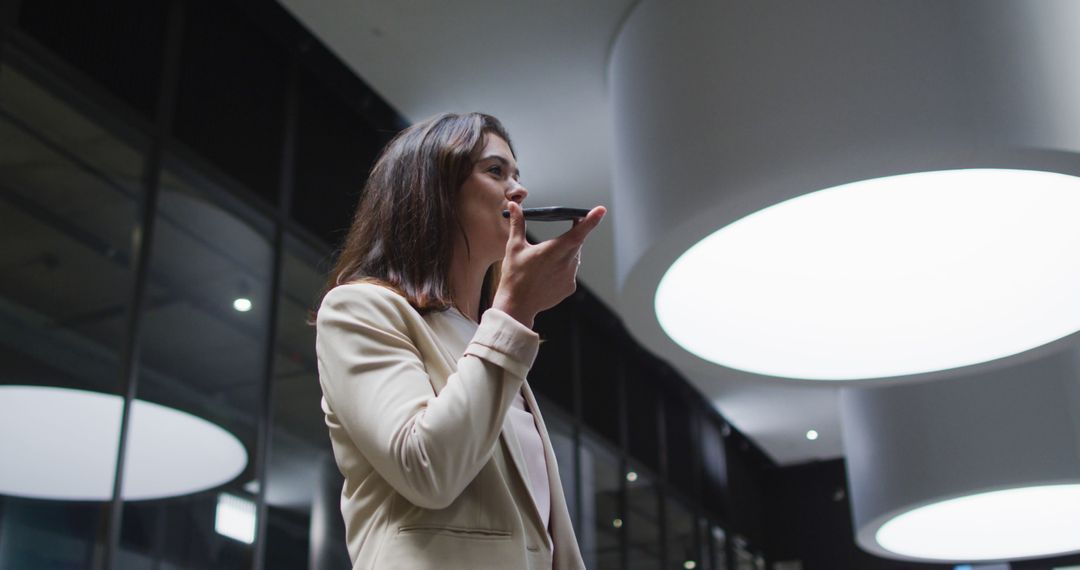 Businesswoman Using Smartphone for Voice Messaging in Modern Office