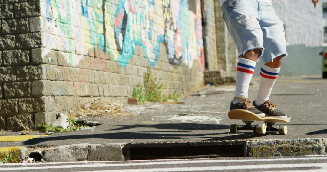 Young Man Skateboarding on Urban Street Near Graffiti Wall - Free Images, Stock Photos and Pictures on Pikwizard.com