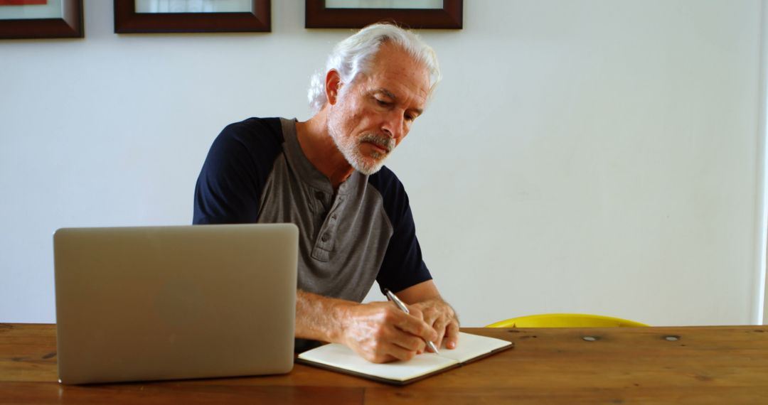 Senior Man Writing in Notebook near Laptop at Home - Free Images, Stock Photos and Pictures on Pikwizard.com