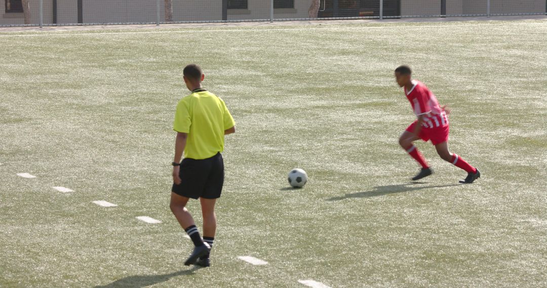 Focused Soccer Player Training with Referee Observing on Field