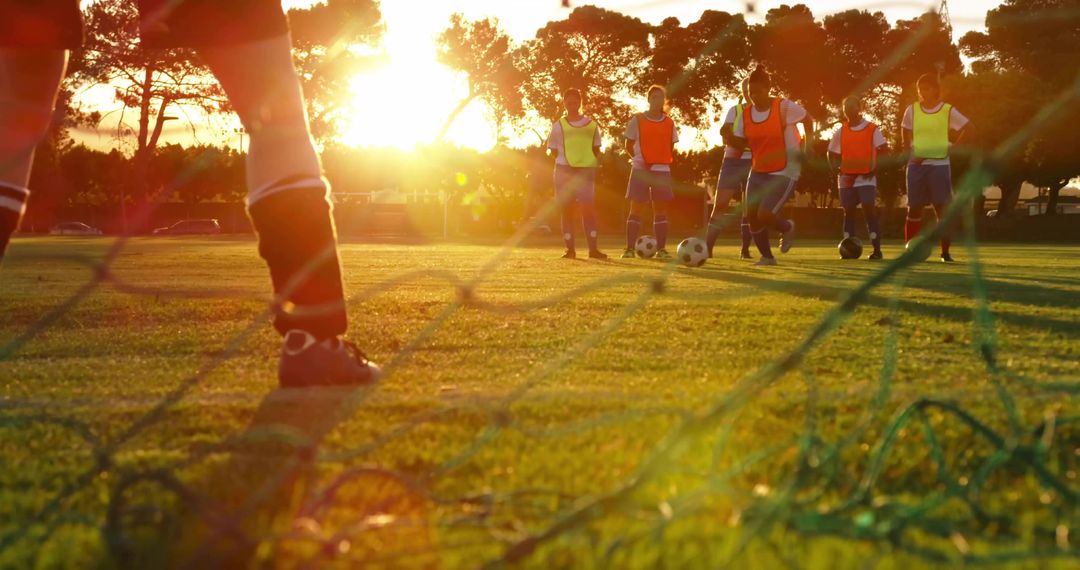 Youth Soccer Practice at Sunset with Goalkeeper and Team