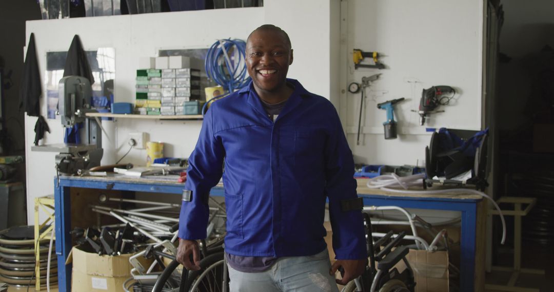 Smiling Mechanic Posing in Workshop Wearing Blue Overhaul - Free Images, Stock Photos and Pictures on Pikwizard.com