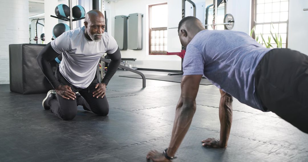 Fitness Trainer Coaches Trainee in Strength Push-Up Exercise at Gym