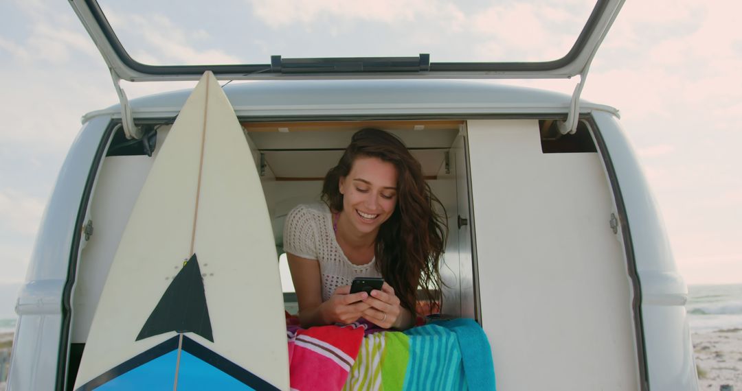 Woman Relaxing in Campervan by Beach Using Phone Next to Surfboard - Free Images, Stock Photos and Pictures on Pikwizard.com