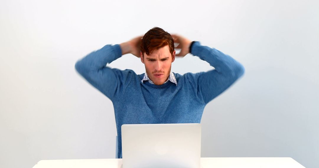 Frustrated Man in Blue Sweater Using Laptop - Free Images, Stock Photos and Pictures on Pikwizard.com