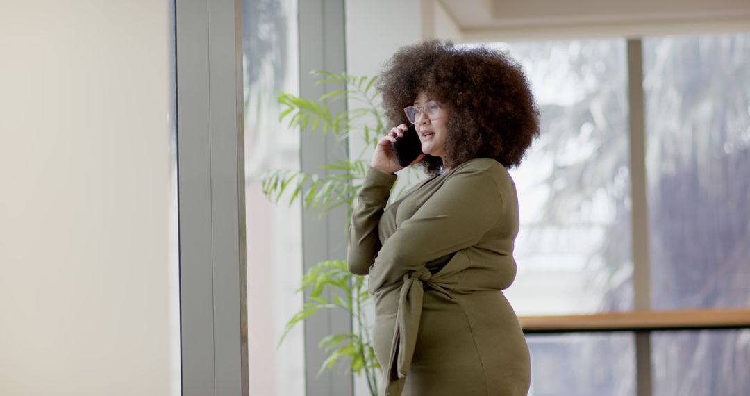 Businesswoman Talking on Phone in Modern Office with Large Windows - Free Images, Stock Photos and Pictures on Pikwizard.com