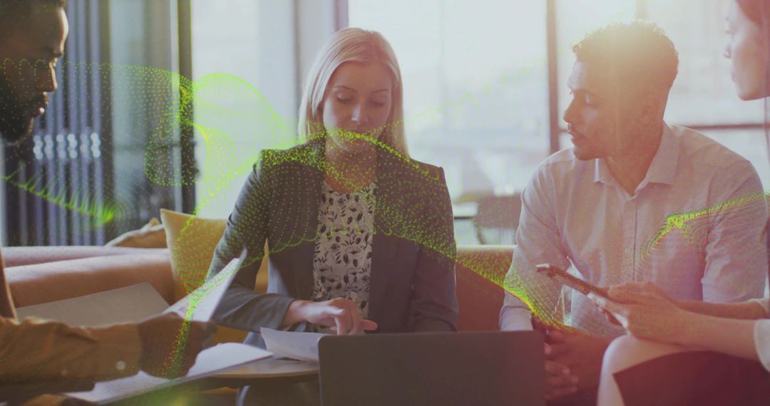 Business team collaborating in lounge around laptop reviewing data and strategy