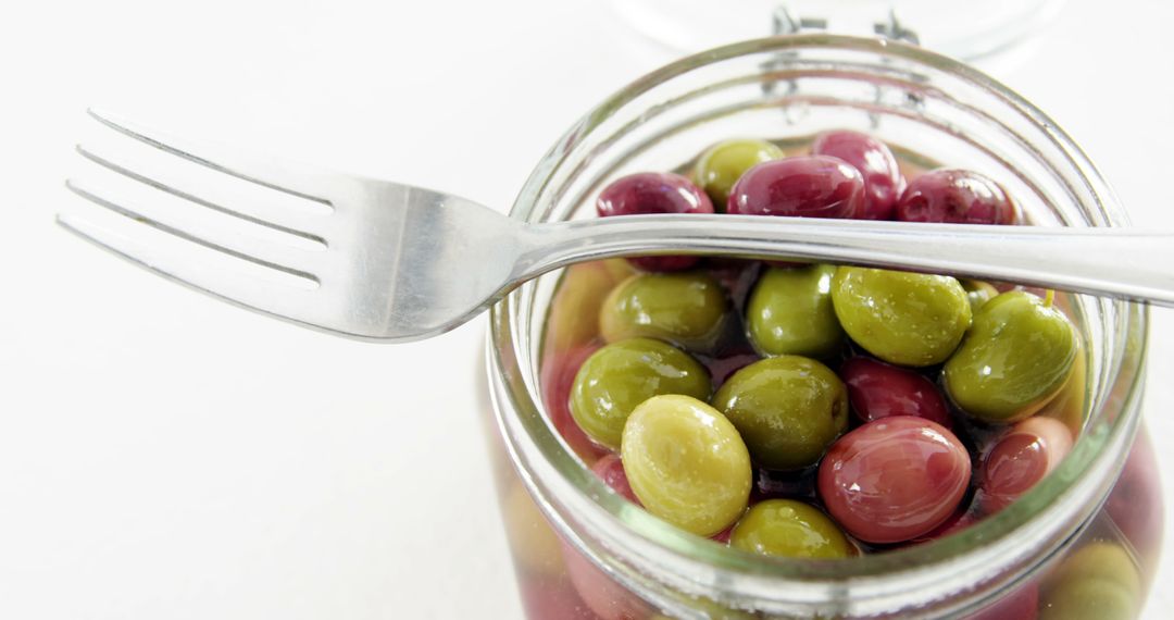 A fork rests on an open jar filled with colorful olives, with copy space - Free Images, Stock Photos and Pictures on Pikwizard.com