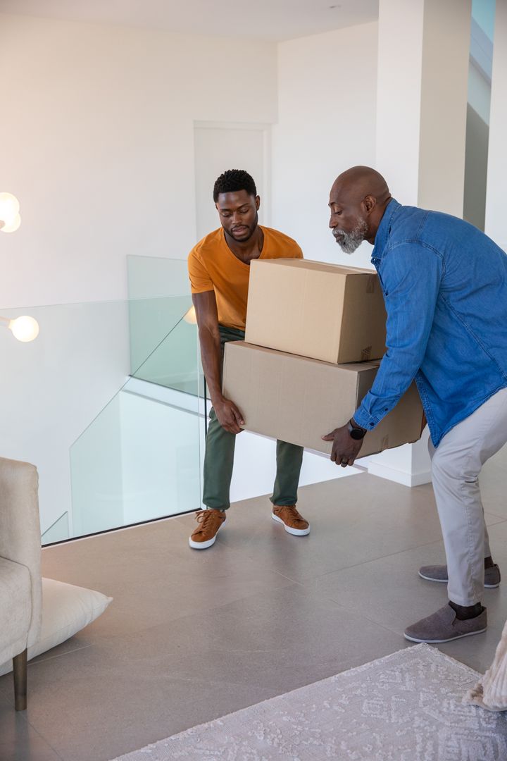 Father and Son Carrying Moving Boxes in Modern Home