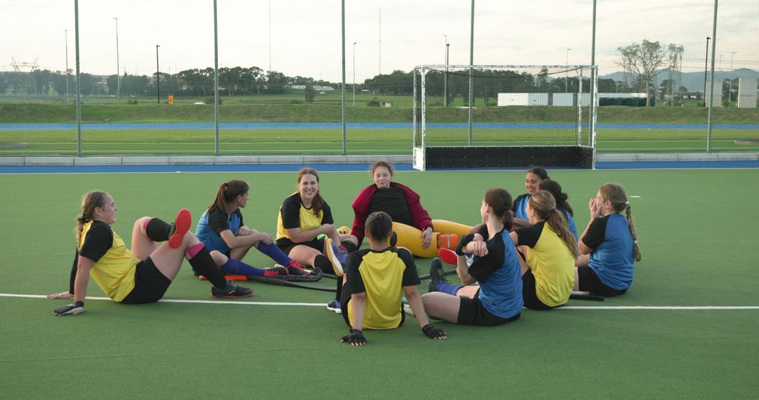 Female Field Hockey Team in Circle Stretching and Socializing