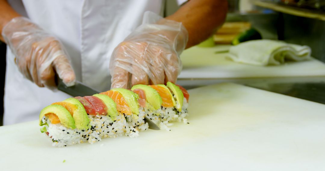 Chef Slicing Fresh Sushi Roll with Seared Fish and Avocado in Commercial Kitchen - Free Images, Stock Photos and Pictures on Pikwizard.com