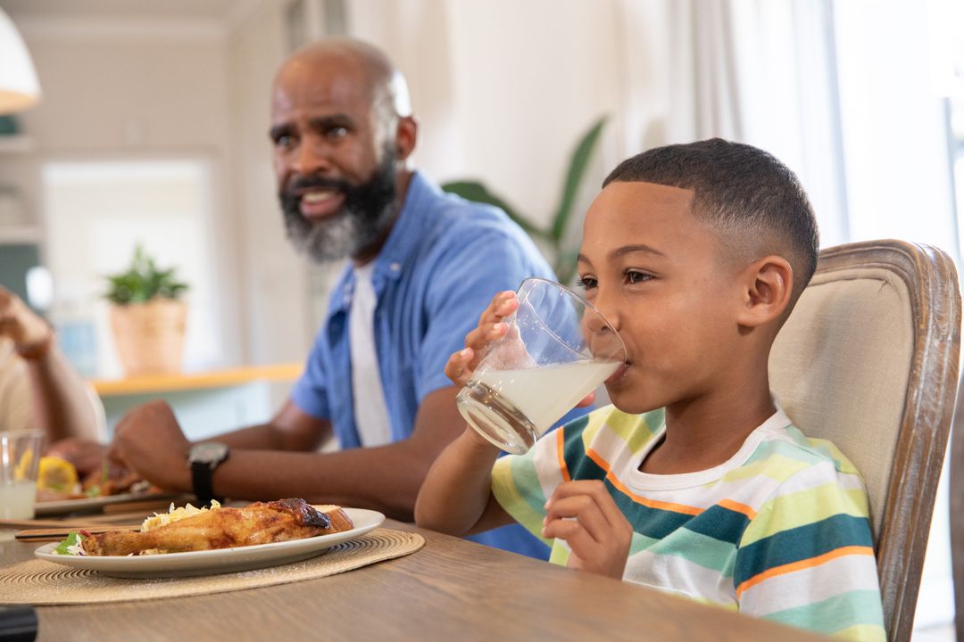 Young Boy Drinking Juice While Enjoying Family Meal