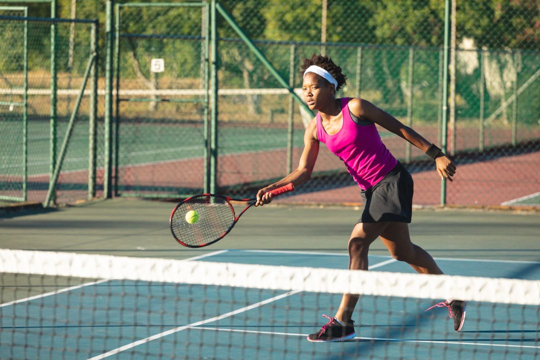 Young female african american tennis player hitting ball with racket while playing at court - Free Images, Stock Photos and Pictures on Pikwizard.com