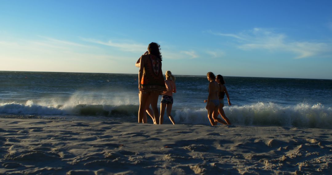 Group of Friends Enjoying Sunny Day at Beach Near Ocean Waves - Free Images, Stock Photos and Pictures on Pikwizard.com