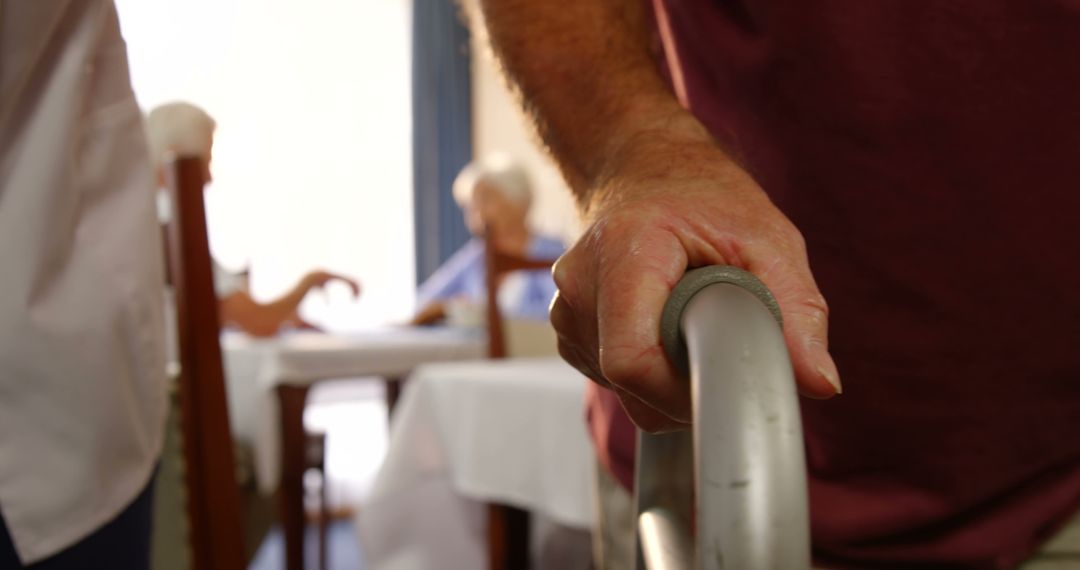 Close-up of senior man holding walking frame with elderly women in background - Free Images, Stock Photos and Pictures on Pikwizard.com