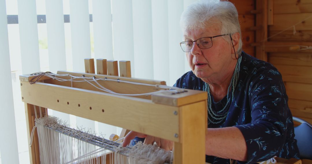 Elderly Woman Weaving on Traditional Loom in Well-Lit Room - Free Images, Stock Photos and Pictures on Pikwizard.com