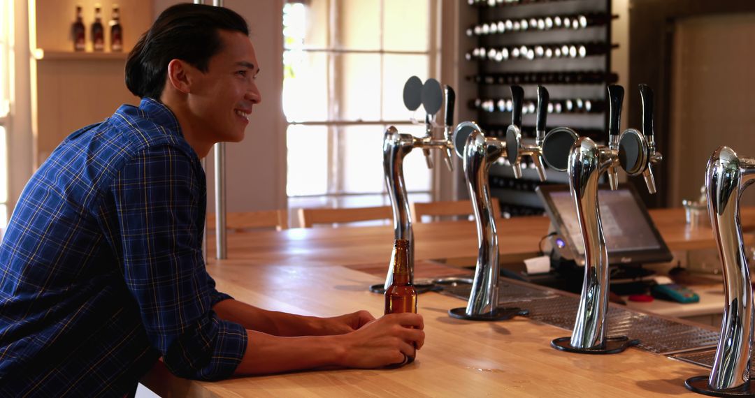 Young Man Relaxing at Bar with Beer Bottle in Hand