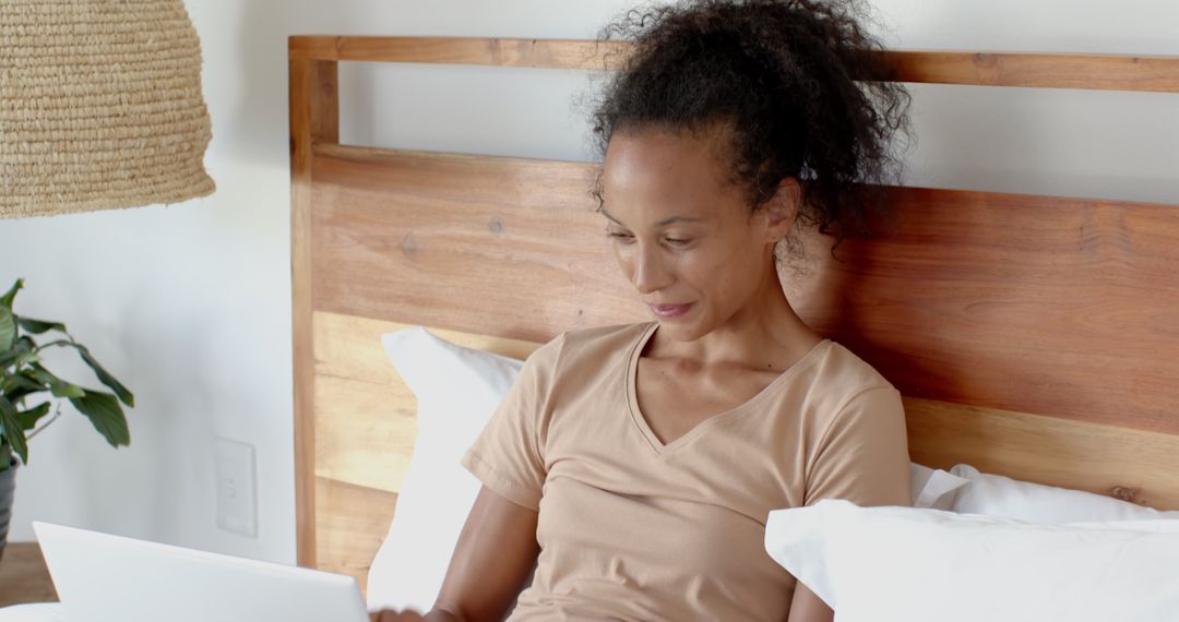 Woman Relaxing in Bed with Laptop, Warm Minimalist Setting