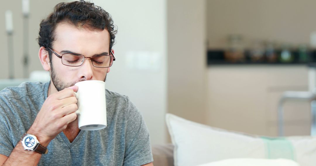 Young Man Sipping Coffee at Home Relaxing - Free Images, Stock Photos and Pictures on Pikwizard.com