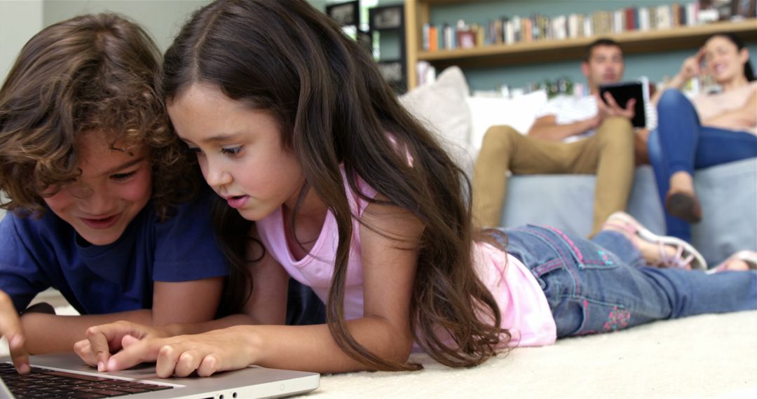 Children Attentively Using Laptop While Parents Relax in Background - Free Images, Stock Photos and Pictures on Pikwizard.com