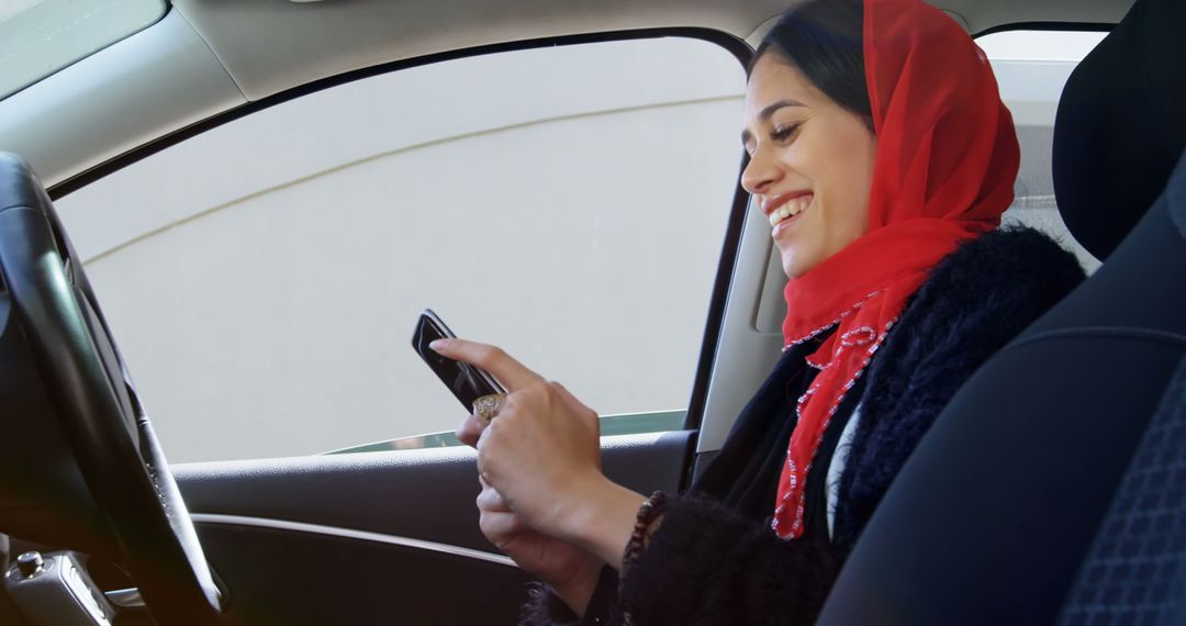 Smiling Woman in Red Hijab Using Smartphone in Car