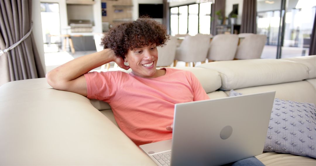 Young Man Relaxing on Sofa Using Laptop in Modern Living Room