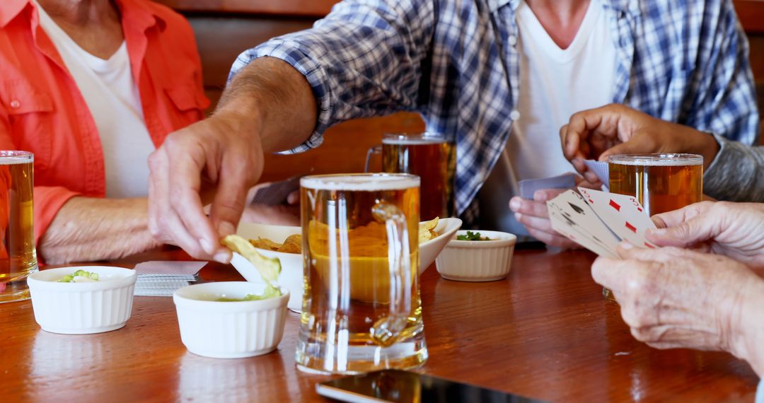 Friends Enjoying Card Game and Refreshments at Pub