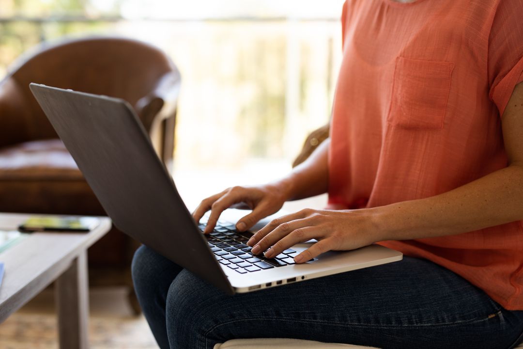 A caucasian woman sitting on a couch in their living room at home while typing on her laptop - Free Images, Stock Photos and Pictures on Pikwizard.com