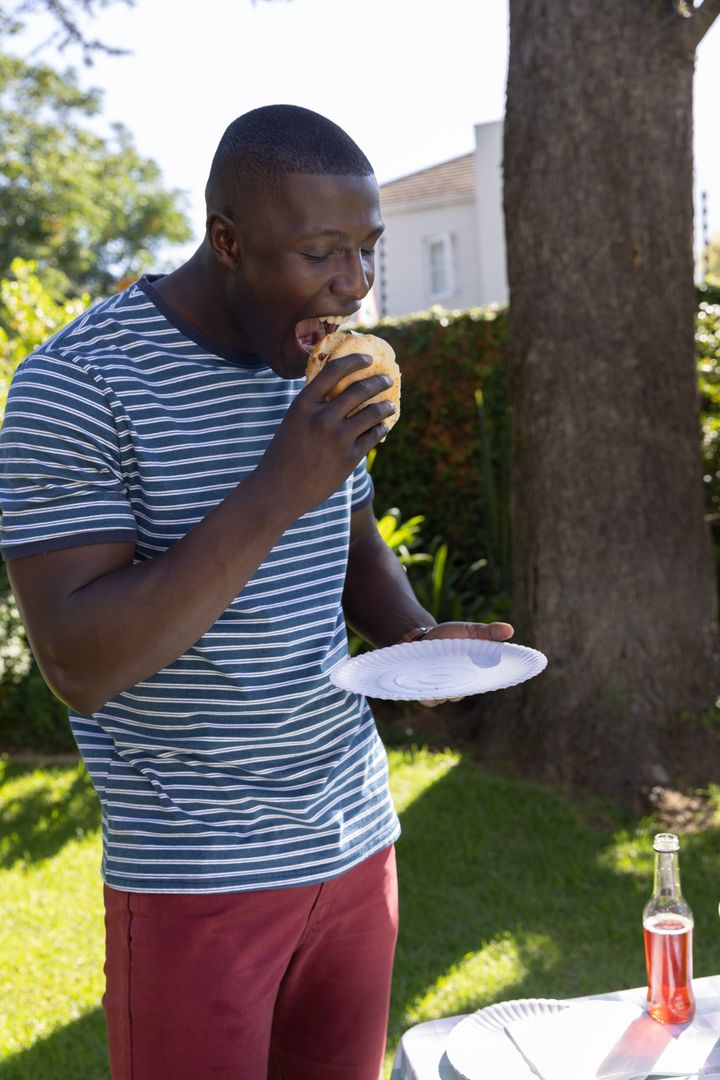 Man Enjoying Hamburger Outdoors in Sunny Backyard