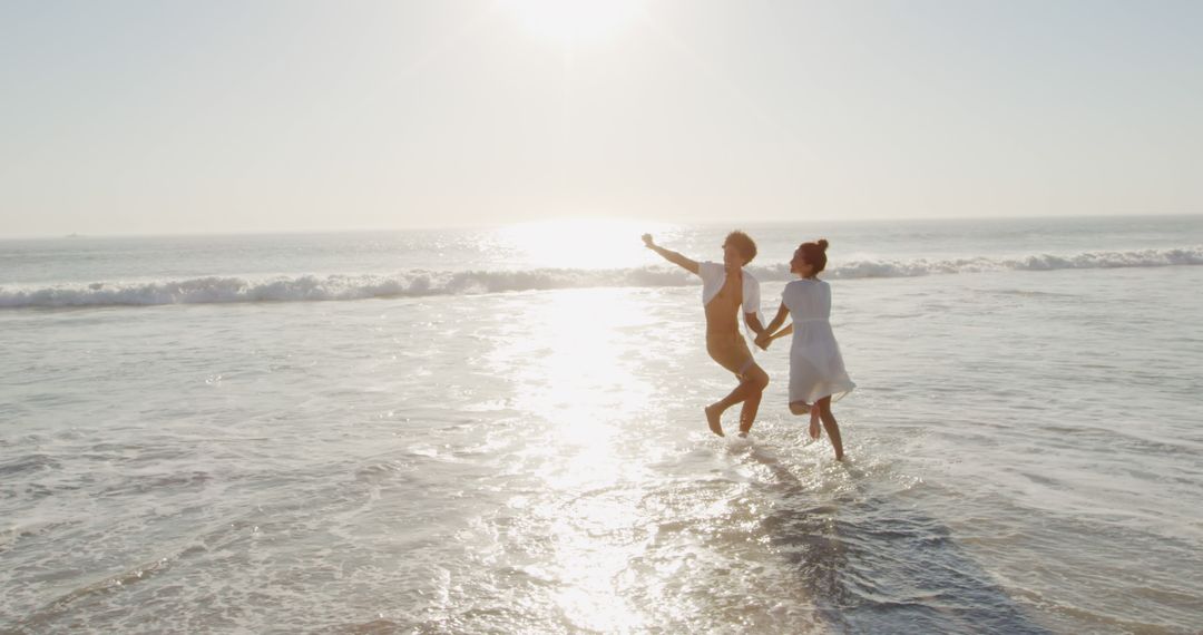 Joyful Couple Splashing in Ocean at Sunset - Free Images, Stock Photos and Pictures on Pikwizard.com