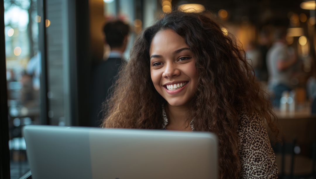 Happy Woman Using Laptop at Cozy Cafe Table